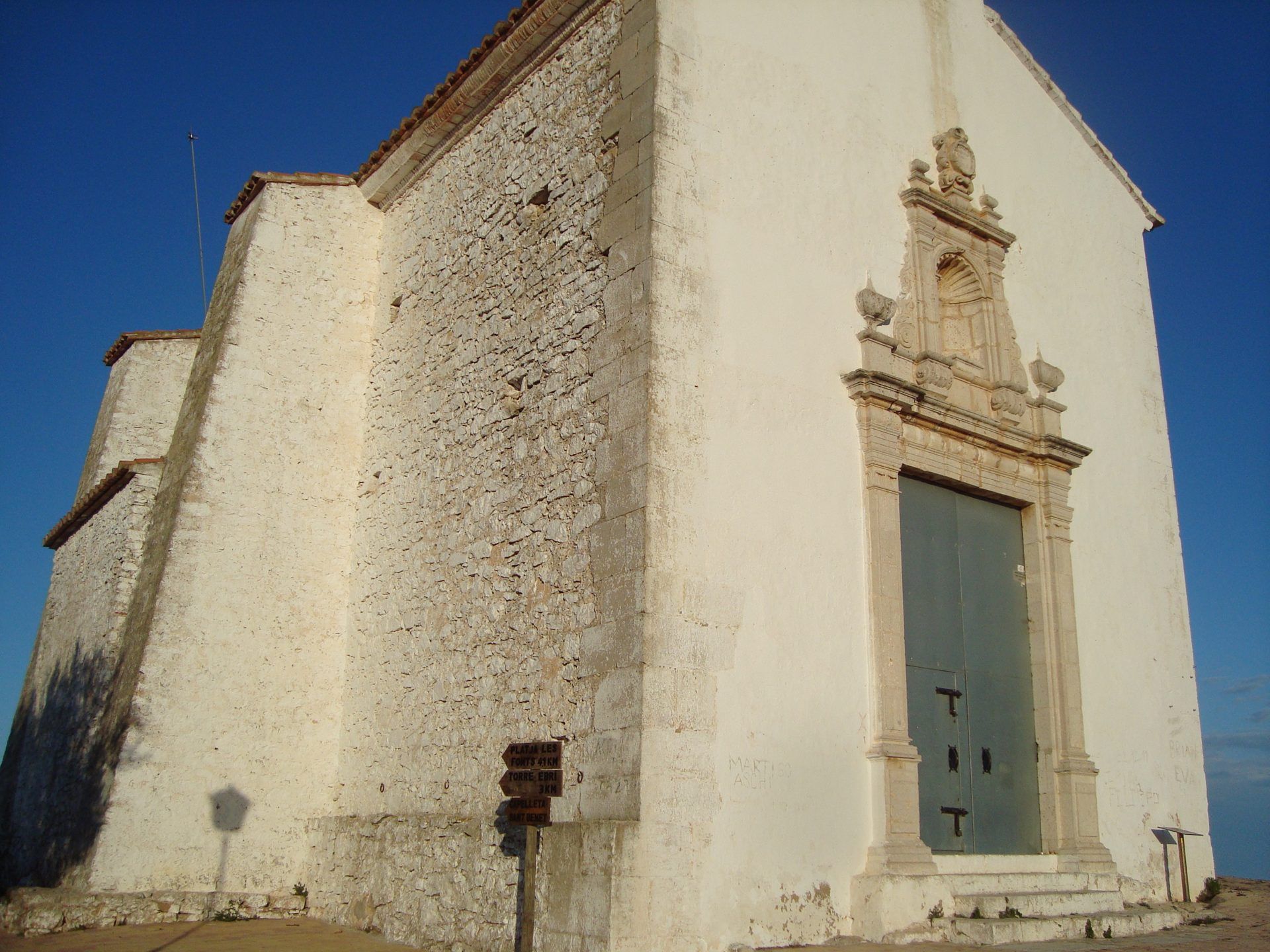 Fachada barroca de la ermita de Santa Lucía y San Benet, en la Sierra de Irta, con el cielo azul de fondo
