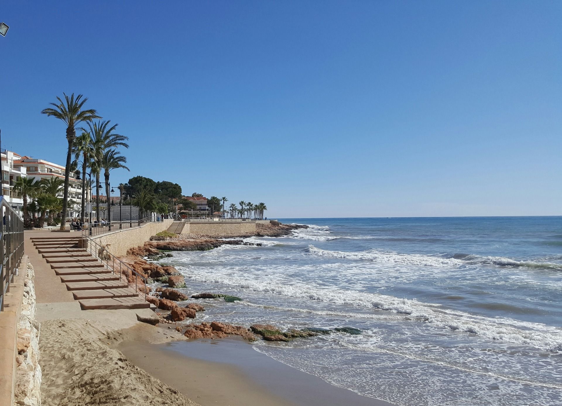Paseo marítimo de Alcossebre con palmeras junto al mar en un día soleado