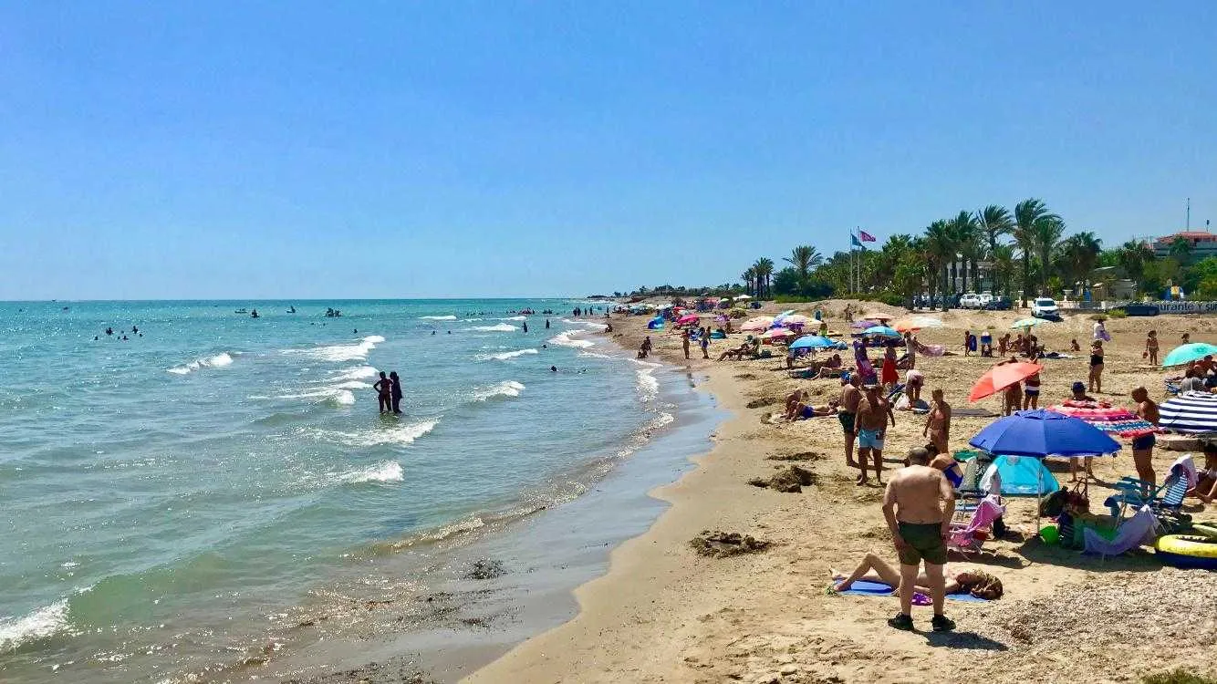 Playa de Alcossebre en verano, con sombrillas y aguas tranquilas